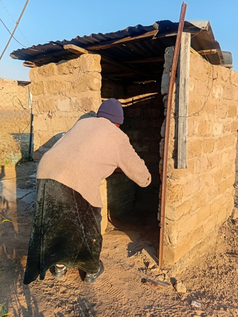IN PHOTOS | No room left to dig: Inside Stinkwater’s pit toilet crisis 6 Elderly woman bends in front of pit toilet structure.