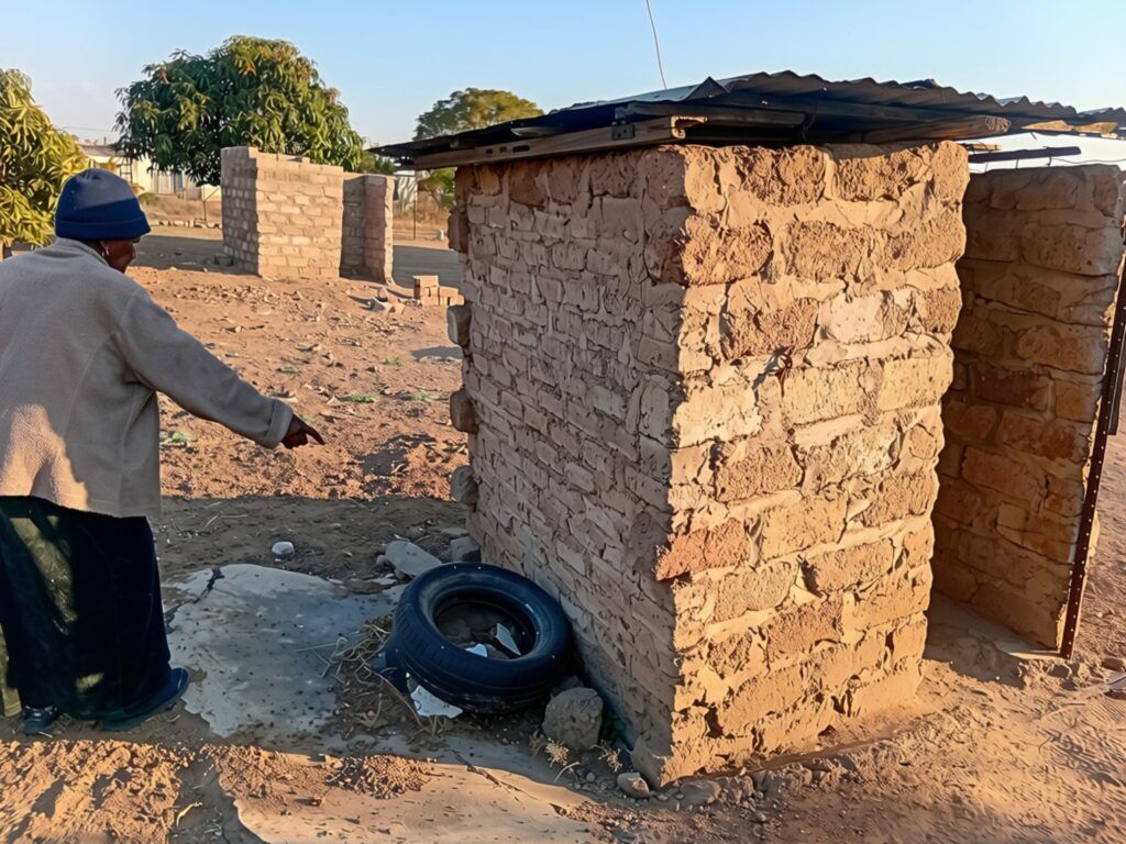 IN PHOTOS | No room left to dig: Inside Stinkwater’s pit toilet crisis 5 Elderly woman points to structure around pit toilet